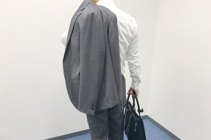 肩からスーツをかける男性